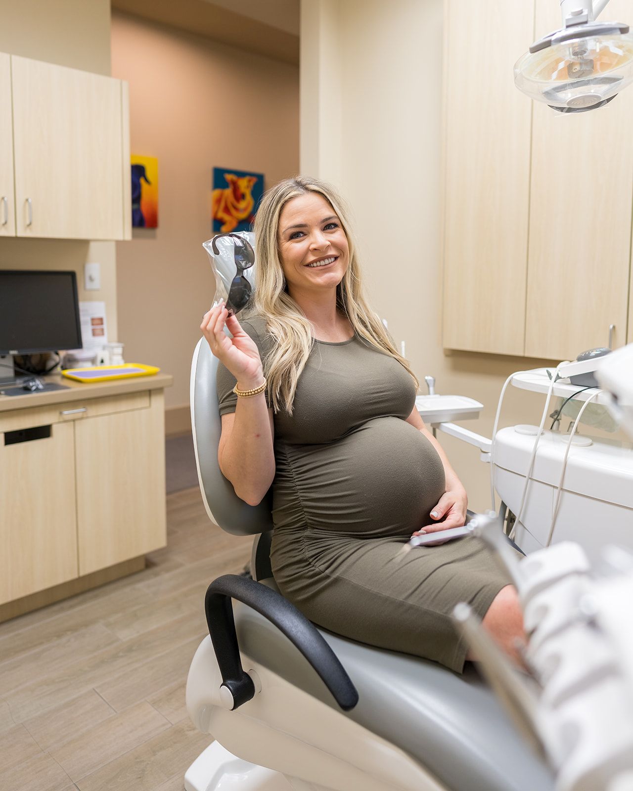 Beautiful pregnant woman sitting in dental chair while smiling with white teeth